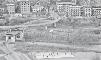  ??  ?? Youths play football near a highway in the capital city of Thimphu.
