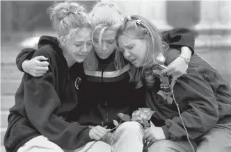  ?? Associated Press ?? ■ Rachel Ruth, Rhianna Cheek and Mandi Annibel, all 16-year-old sophomores at Heritage High School in Littleton, Colo., console each other April 21, 1999, during a vigil service to honor the victims of the shooting spree at Columbine High School in the southwest Denver suburb of Littleton. Twelve students and one teacher were killed in a murderous rampage at the school on April 20, 1999.