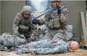  ?? Jerry Lara / San Antonio Express-News ?? After hacking their way through a sheet metal barrier, Sgt. Joseph Batres, left, and Capt. Chase Morris work on a dummy during the Army Best Medic Competitio­n at Camp Bullis in San Antonio.