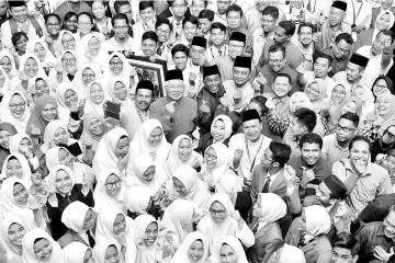  ?? - Bernama photo ?? Datuk Seri Najib Tun Razak showing the ‘Finger Heart’ signals at the Parit Umno delegates conference with students of Maktab Rendah Sains MARA.