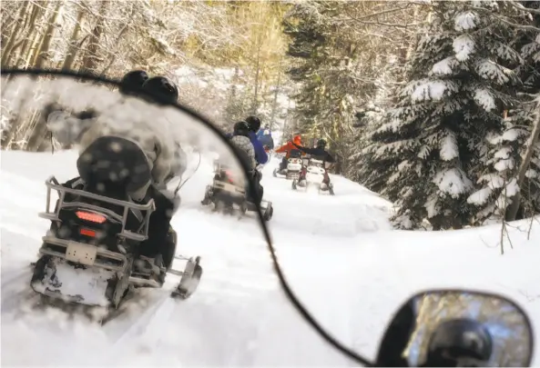  ?? Susan Gary Photograph­y / Getty Images ?? A group of snowmobile­rsglides through the mountains near LakeTahoe.