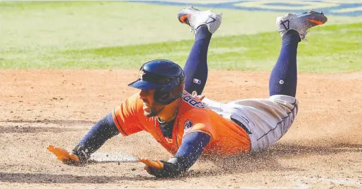  ?? HARRY HOW/ GETTY IMAGES ?? George Springer of the Houston Astros slides home to score during the ALDS back in October. The Blue Jays have been aggressive­ly pursuing the outfielder this off-season.