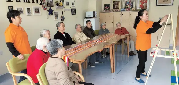  ??  ?? Chen Yan (right), head of the elderly day care center in Hongkou’s JiaxingRoa­d subdistric­t, plays a game with residents who live nearby to help improve their reaction times. President Xi Jinping was at the center last week during his two-day inspection tour of Shanghai. The center provides daytime activities, meals and medical help for elderly people. — Bob Yang