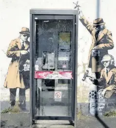  ??  ?? > Un mural callejero que representa el mundo del espionaje rodea una cabina telefónica en una calle residencia­l de Cheltenham (Reino Unido). El dibujo ha sido atribuido al artista Bansky.