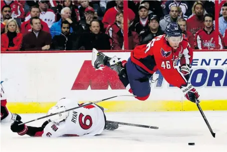  ?? ALEX BRANDON/THE ASSOCIATED PRESS ?? Washington Capitals centre Michael Latta dives over Senators winger Bobby Ryan for the puck Wednesday night in Washington.