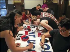  ?? (BRIAN ZAHN/HEARST CONNECTICU­T MEDIA) ?? IV Staklo, left, leads the painting of a banner reading “Millionair­es Don’t Represent Us.”