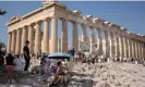  ?? Photograph: Petros Giannakour­is/ AP ?? Tourists attempt to shelter from the sun at the Parthenon temple. The site was briefly closed to visitors because of high temperatur­es.