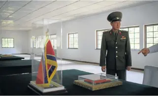  ?? /AFP ?? Truce town: A North Korean soldier stands before a copy of the armistice agreement displayed inside the Armistice Hall on the north side of the truce village of Panmunjom, in the demilitari­sed zone separating North and South Korea.