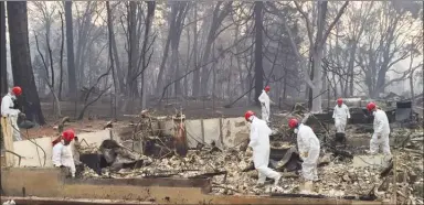  ?? The Associated Press ?? Volunteer rescue workers search for human remains in the rubble of homes burned in the Camp Fire in Paradise, Calif., last week. Authoritie­s continue to log hundreds of reports by people who couldn't reach loved ones there.