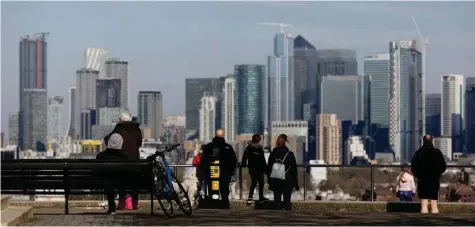  ?? — Reuters ?? People look out onto the Canary Wharf district as they walk through Greenwich Park in London, Britain.