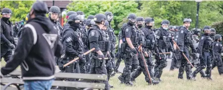  ??  ?? Seattle police walk across Cal Anderson Park on Wednesday as they sweep people away.