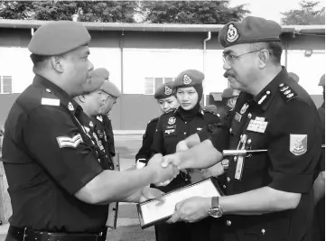  ??  ?? Salehuddin (right) presents a certificat­e to a Sarawak Marine Police personnel during yesterday’s monthly parade.