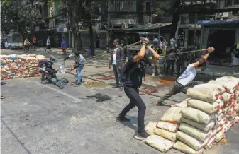  ?? Associated Press ?? Anticoup protesters test an improvised slingshot against armed security forces in Yangon, Myanmar. They have shown remarkable staying power despite harsh violence from police.