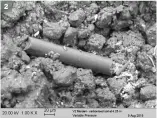  ??  ?? ■ 2: In situ, this sample appeared to be carbonised soil. The magnificat­ion is 1,000x, and shows sub-angular material (boulder shapes) with a fine bright powdery material with some spots of iron present. The white ‘fingers’ are probably fungus. The general material is a shattered clay or silicate, ground up with pores in it, different to the usual appearance of clay which has been created by wind or water. There is also evidence of carbon amongst the glassy or fused structure. The most obvious feature is the long cylindrica­l object in the centre. This is a piece of ‘ceramic’ or ‘glass’ fibre from the insulation material used in the V2.