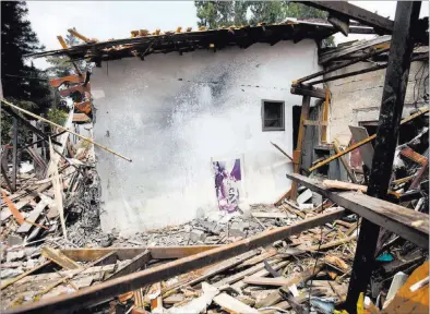  ?? DAN BALILTY/ THE ASSOCIATED PRESS ?? A rocket fired by Hamas on Tuesday destroyed this house in Yehud, in central Israel near Ben Gurion Internatio­nal Airport, injuring one person and prompting the Federal Aviation Administra­tion to issue a ban on U.S. flights to Israel over the country’s...