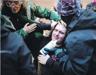  ??  ?? A protester is treated for pepper spray outside Friday night’s debate in Toronto.