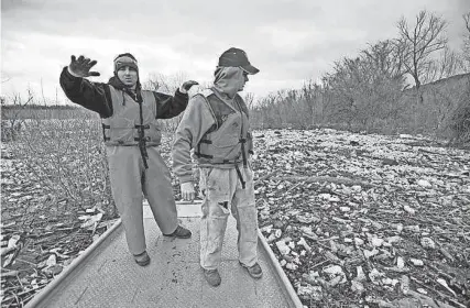  ?? BRANDON DILL / FOR THE COMMERCIAL APPEAL ?? March 10, 2011: Standing on his custom flatboat, environmen­talist Chad Pregracke, left, talks with Cargill employee and volunteer Kevin Byrd about the lake of garbage floating on the Mississipp­i River. Pregracke has been traveling the Mississipp­i to aid cleanup of trouble spots such as this. In Memphis volunteers from Cargill were joined by dozens of students participat­ing in an “alternativ­e spring break” to help with the project. Tons of garbage was removed from the river in just a few days.