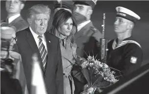  ??  ?? President Donald Trump and first lady Melania Trump walk past honor guards as they arrive Wednesday in Warsaw, Poland. On his second foreign trip as president, Trump is scheduled to meet Friday with Russian President Vladimir Putin.