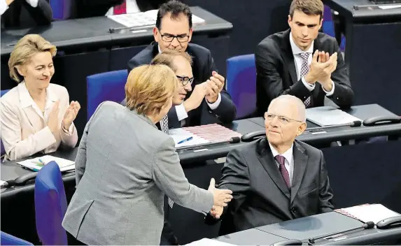  ?? Byl včera do čela Bundestagu zvolen poslanec, jenž je i služebně nejstarší: 75letý dosavadní ministr financí Wolfgang Schäuble (CDU). Na snímku přijímá gratulaci od kancléřky. FOTO REUTERS ?? Vůbec poprvé