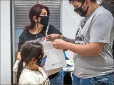  ??  ?? Liliana Lopez and her children, Mariana Lenis, 7, and Bryan Lopez receive services from the Latino Community Center, which is running a vaccine awareness campaign to encourage local Latino people to get the COVID-19 vaccine.