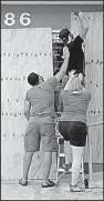  ?? AP/CARLOS GIUSTI ?? Helpers support Christophe­r Rodriguez as he puts plywood over a storefront window Tuesday in Toa Baja, Puerto Rico. “This is an extremely dangerous storm,” Puerto Rico Gov. Ricardo Rossello said.