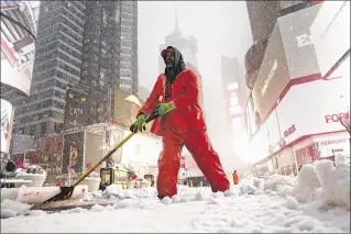  ?? CAROLYN COLE / LOS ANGELES TIMES ?? New York City employee Ronney Wade shovels snow Tuesday in Times Square. A storm fell well short of the forecast snow totals in New York but unloaded 1 to 2 feet in many places inland.