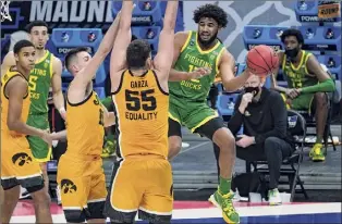  ?? Paul Sancya / Associated Press ?? Oregon guard LJ Figueroa passes around Iowa center Luka Garza on Monday. The Ducks took down the No. 2-seeded Hawkeyes after a first-round walkover.