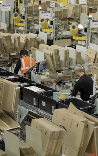  ??  ?? Impegno Ecco alcuni lavoratori di Amazon a Passo Corese impegnati nel preparare i pacchi