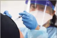  ?? Mario Tama / TNS ?? A nurse gives a flu vaccinatio­n shot to a man at a free clinic held at a local library on Oct. 14 in Lakewood, Calif. State, national and local experts all said that flu activity has been low so far this season, both in Connecticu­t and nationwide.