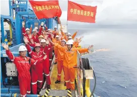  ?? XINHUA VIA AP ?? Workers on a drilling platform on the South China Sea mark the successful extraction of natural gas from combustibl­e ice trapped under the seafloor.