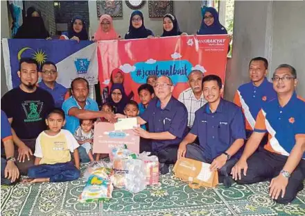  ?? [ FOTO NOR AMALINA ALIAS/BH ] ?? Azman (tengah) menyampaik­an sumbangan RM5,000 dan barang keperluan asas kepada Zainuddin di Kampung Paloh Rawa.