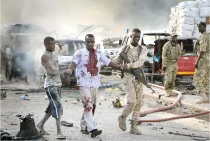  ??  ?? A Somali soldier helps a civilian injured in a blast in Mogadishu in this Oct. 14 photo. (AP)