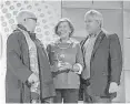  ??  ?? Sherry Chris, president and CEO of Better Homes and Gardens Real Estate (left), presents awards to Gary Greene managing partners Marilyn Eiland and Mark Woodroof as the brand’s top-producing company for both units closed and volume in 2016.