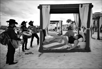  ?? AP PHOTO/EMILIO ESPEJEL ?? Roving musicians “Los Compas” serenade a couple on the shore of Mamitas beach, in Playa del Carmen, Quintana Roo state, Mexico, on Jan. 5. Mexico saw a holiday bump in tourism amid the new coronaviru­s pandemic surge.