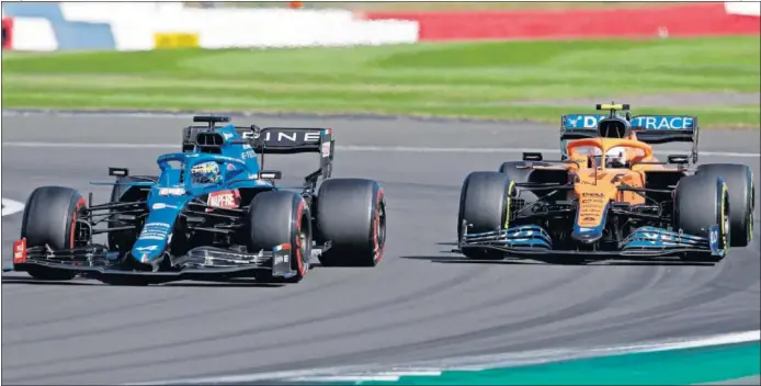 ??  ?? Fernando Alonso se defiende, con su Alpine, de Lando Norris y su McLaren durante la carrera al esprint celebrada ayer en el circuito de Silverston­e.
