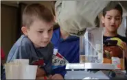  ?? KELSEY LEYVA — THE MORNING JOURNAL ?? Ian Kilgore, an 8-year-old second-grader at Avon East Elementary School, watches as Oberlin College Professor Jason Belitsky creates a slimy gel April 14 during the Get with the Program “Chemistry” STEM camp at Oberlin College’s Austin E. Knowlton...