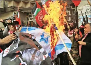  ?? MOHAMMED ABED/AFP ?? Palestinia­n protestors burn the Israeli flag and a poster of US President Donald Trump in Gaza City yesterday.