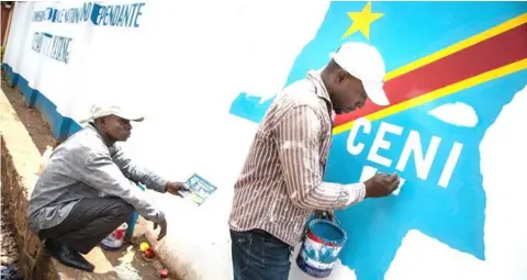  ?? — AFP photo ?? Workers paint a logo of the Independen­t National Election Commission (CENI) in Lubumbashi. The sprawling central African country is in the grip of a two-year-old crisis over elections for a successor to President Joseph Kabila, in power since 2001.