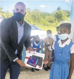  ??  ?? Dane Patterson presents a tablet to Church Hill Primary School student Kimielia Hall.