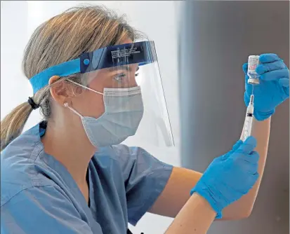  ?? MATT STONE / BOSTON HERALD ?? Dr. Marisa Tieger, a physician at Massachuse­tts Eye and Ear, fills a needle with the Moderna COVID-19 vaccine at a Brookline clinic.