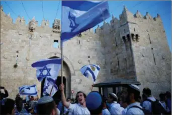  ?? AP PHOTO/ARIEL SCHALIT ?? Israelis wave national flags outside the Old City’s Damascus Gate, in Jerusalem, Sunday, May 13, 2018.