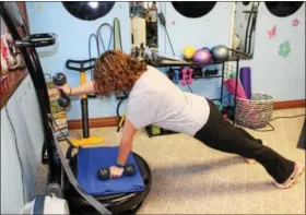  ??  ?? Shannon Anthony does a plank with weights while using a vibration exercise machine. Anthony is the owner of Serenity Fitness & Wellness in Boyertown.