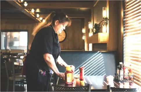  ??  ?? A waitress prepares for the first customers of the day at the The Shed, which re-opened in December after its old owner was deported. It remains a popular spot for locals, and many employees have worked there for years, but they were unwilliing to...