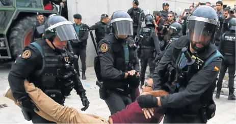  ?? /AFP Photo ?? Ballot blitz: Members of the Spanish Civil Guard drag a man outside a polling station in Sant Julia de Ramis, where Catalan leader Carles Puigdemont was supposed to cast his vote on Sunday. Puigdemont, who described the violence as disproport­ionate,...