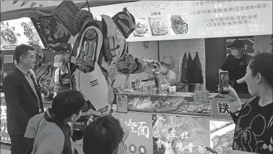  ?? CHEN YUYU / FOR CHINA DAILY ?? Visitors watch as a Transforme­r cosplayer buys food at a street stall market in Shanghai in May.