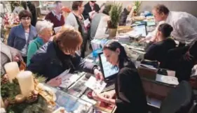  ??  ?? Visitors buy Christmas post stamps and send letters at a post office in the village of Christkind­l.