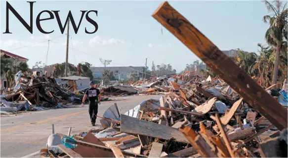  ?? AP PHOTO ?? Logan Brisson of the Sarasota County Fire Dept. strike team, walks past debris in the aftermath of Hurricane Michael in Mexico Beach, Fla., on Thursday.