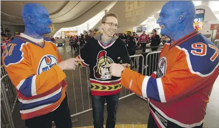  ?? DAVID BLOOM ?? Edmonton Oilers’ fans Dean Ostafichuk and Jimmy Pietrarca make some good-natured points about the team to Ottawa fan Stuart Thomson in Ford Hall at Rogers Place.