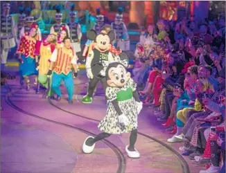  ?? Photograph­s by Allen J. Schaben Los Angeles Times ?? MICKEY and Minnie Mouse lead a fashionabl­e parade in the Mickey’s Toontown area of Disneyland on March 7 that featured Opening Ceremony’s spring collection and its new Disney collection.