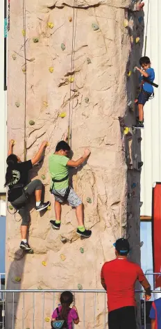  ??  ?? The young and old test their skills on the rock climbing wall.